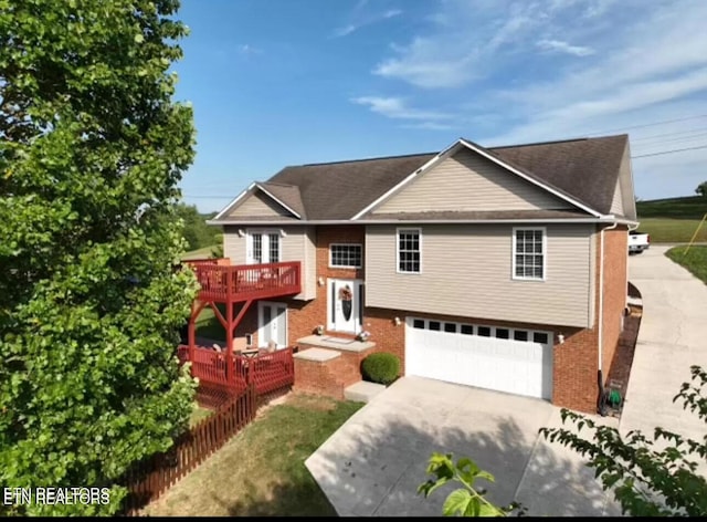 raised ranch featuring concrete driveway, a balcony, brick siding, and a garage