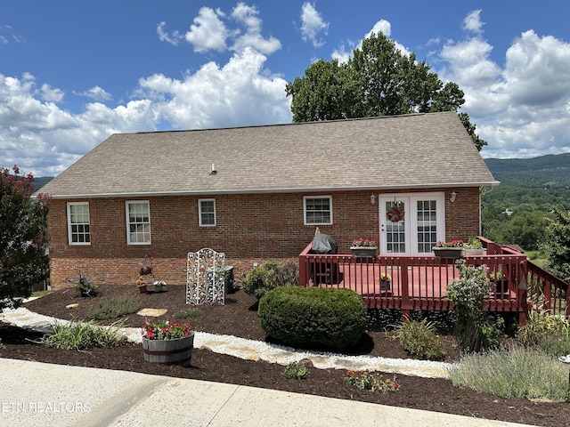 back of property featuring brick siding, a wooden deck, and a shingled roof