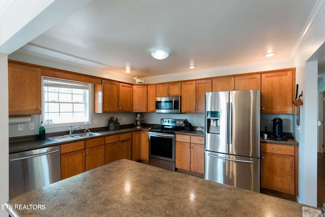 kitchen with dark countertops, brown cabinets, appliances with stainless steel finishes, and a sink