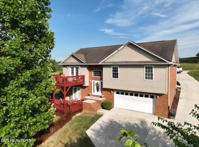 raised ranch featuring brick siding, concrete driveway, and an attached garage