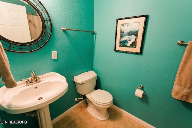 bathroom with tile patterned flooring, toilet, baseboards, and a sink