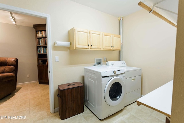 clothes washing area featuring washer and clothes dryer, light tile patterned floors, cabinet space, and baseboards