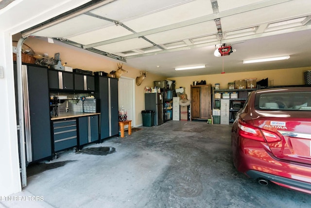 garage featuring a garage door opener and freestanding refrigerator