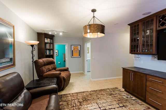 living room featuring baseboards, light tile patterned flooring, and track lighting