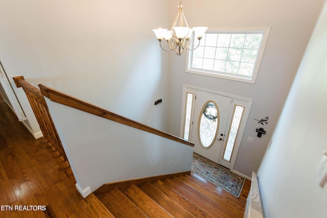 entrance foyer with dark wood finished floors, a towering ceiling, baseboards, a chandelier, and stairs