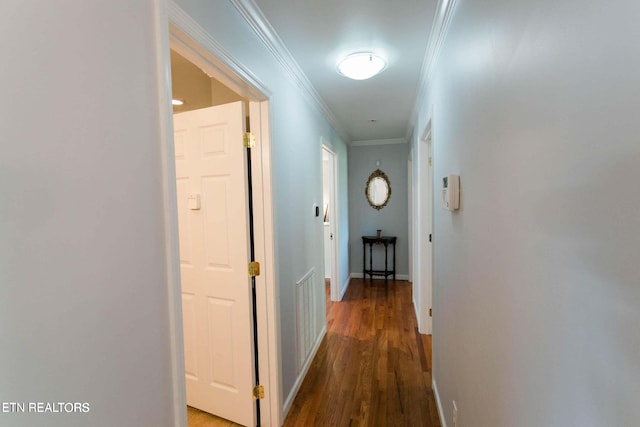 hall featuring visible vents, baseboards, wood finished floors, and crown molding