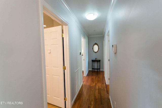 hallway featuring wood finished floors, baseboards, ornamental molding, and visible vents