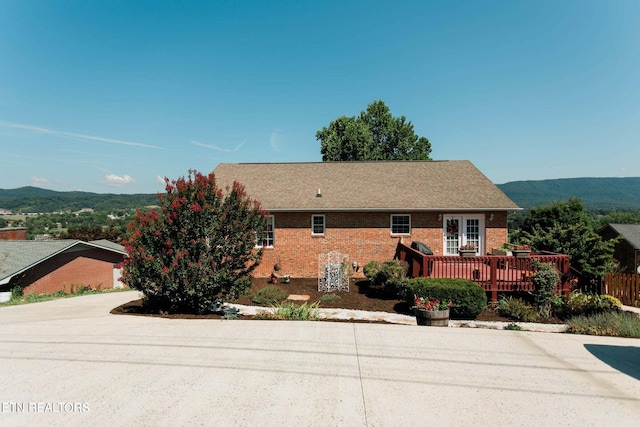 view of front facade featuring a deck with mountain view, concrete driveway, and brick siding