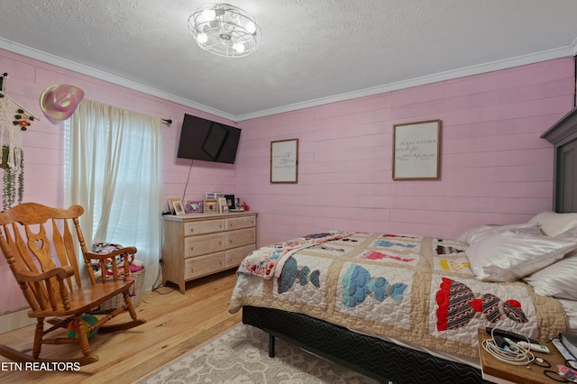 bedroom featuring light wood finished floors, a textured ceiling, and ornamental molding