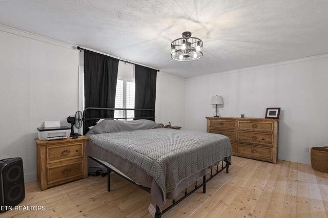 bedroom featuring a textured ceiling, light wood-style flooring, a notable chandelier, and ornamental molding