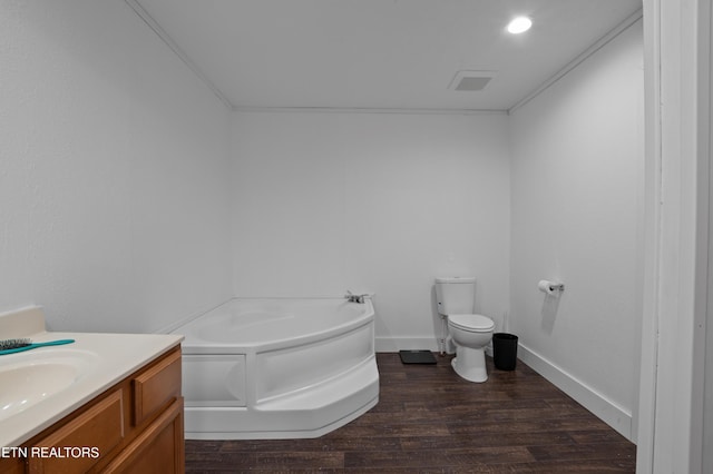 bathroom with a garden tub, toilet, wood finished floors, baseboards, and vanity