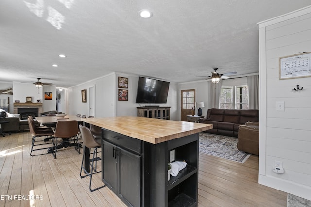 kitchen featuring open floor plan, dark cabinetry, butcher block countertops, and ceiling fan