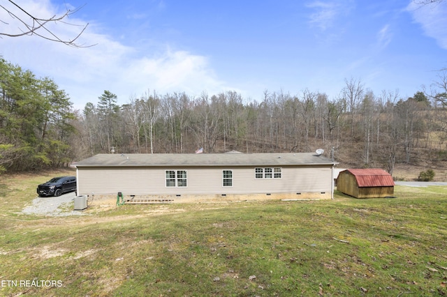 back of property featuring an outbuilding, a storage unit, a yard, and crawl space