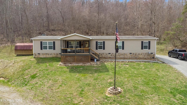 manufactured / mobile home with a front yard, a forest view, and crawl space