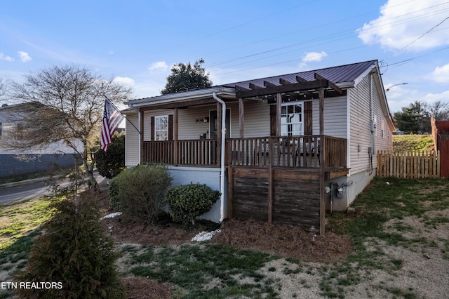 view of front facade with metal roof, covered porch, and fence