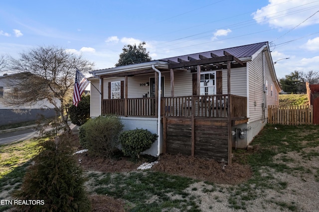 view of front of property featuring metal roof, covered porch, and fence