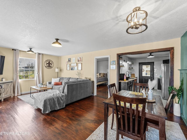 dining area featuring dark wood finished floors, an inviting chandelier, and a textured ceiling