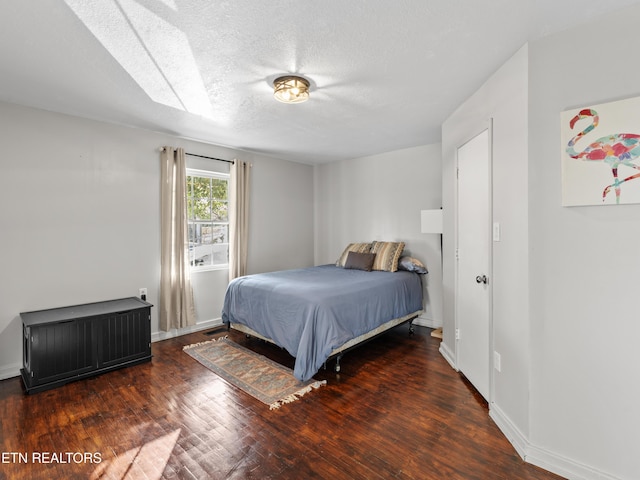 bedroom with wood finished floors, baseboards, and a textured ceiling