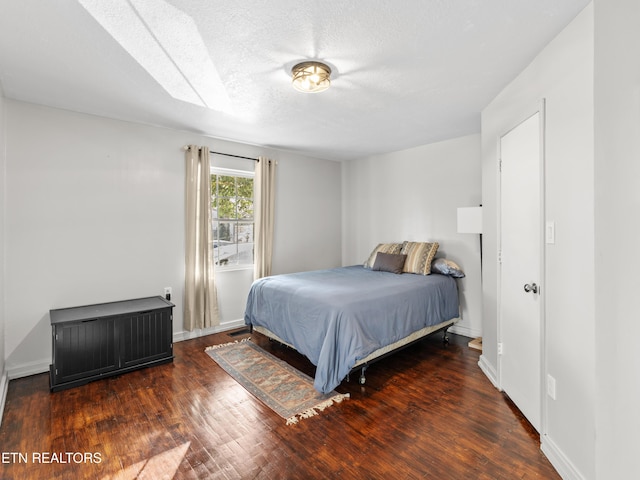 bedroom featuring a textured ceiling, baseboards, and wood finished floors