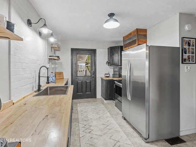 kitchen with a sink, open shelves, stainless steel appliances, wall chimney range hood, and glass insert cabinets