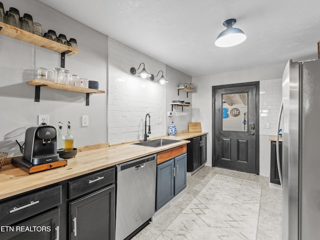 kitchen with backsplash, open shelves, butcher block countertops, stainless steel appliances, and a sink