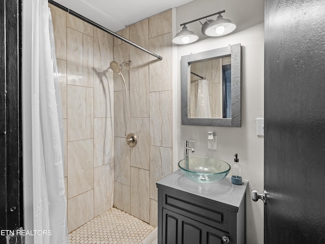 bathroom featuring tiled shower and vanity