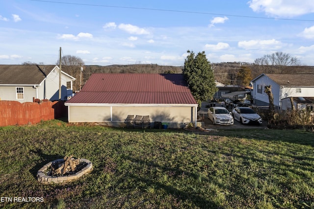 view of side of property with a fire pit, metal roof, a lawn, and fence