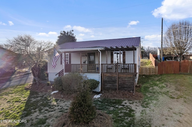 bungalow-style home with metal roof, a porch, a front yard, and fence