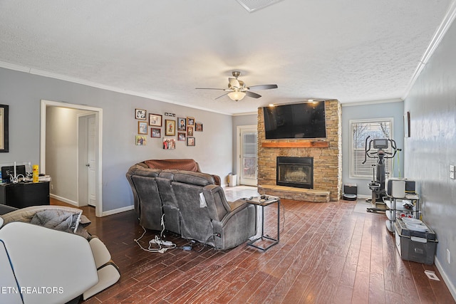 living area featuring wood finished floors, baseboards, a stone fireplace, a textured ceiling, and crown molding