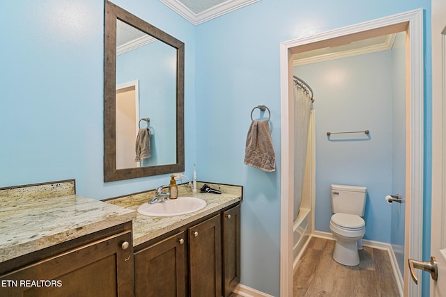 bathroom featuring vanity, wood finished floors, baseboards, ornamental molding, and toilet