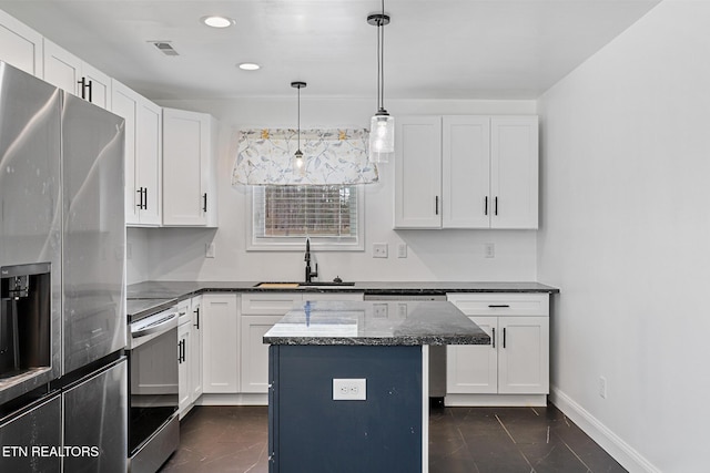 kitchen featuring a center island, dark stone countertops, appliances with stainless steel finishes, white cabinets, and a sink