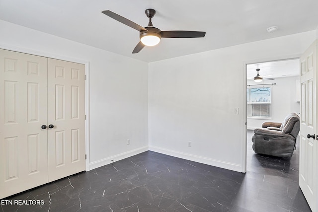 empty room featuring a ceiling fan, baseboards, and marble finish floor