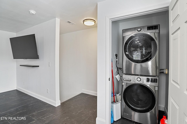 washroom with visible vents, baseboards, laundry area, and stacked washing maching and dryer