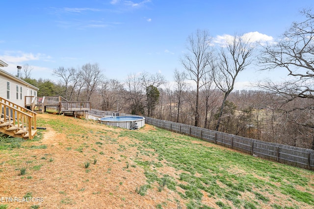 view of yard with a wooden deck, a fenced backyard, and stairway