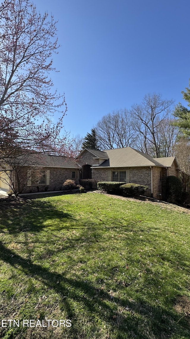 rear view of property with a lawn and brick siding