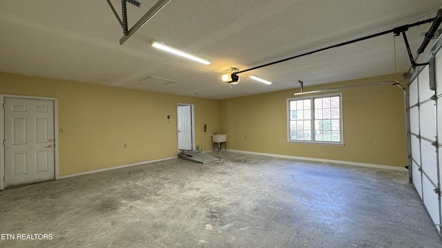 garage featuring a garage door opener, baseboards, and a sink