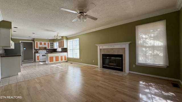 unfurnished living room with a tiled fireplace, crown molding, visible vents, and light wood-type flooring