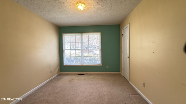 carpeted spare room featuring visible vents, a textured ceiling, and baseboards