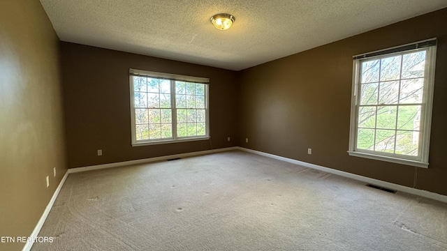 unfurnished room with baseboards, visible vents, carpet floors, and a textured ceiling