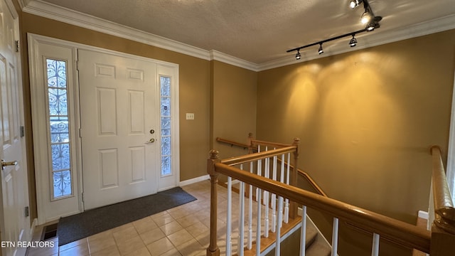 entryway featuring a textured ceiling, ornamental molding, and tile patterned flooring