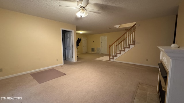 basement featuring baseboards, carpet, stairs, a textured ceiling, and a ceiling fan