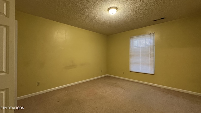 carpeted spare room with baseboards, visible vents, and a textured ceiling