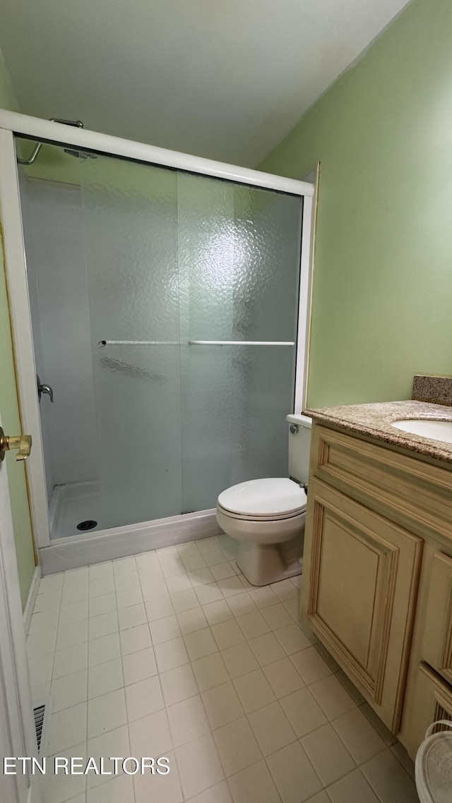 full bathroom with a stall shower, toilet, tile patterned flooring, and vanity