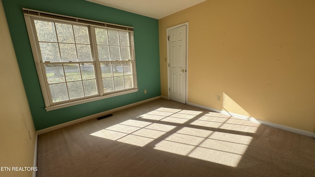 carpeted empty room featuring baseboards and visible vents