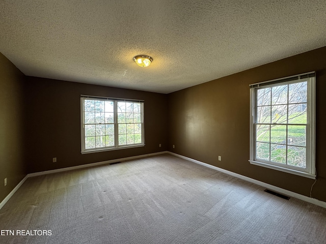 empty room with baseboards, visible vents, and carpet flooring