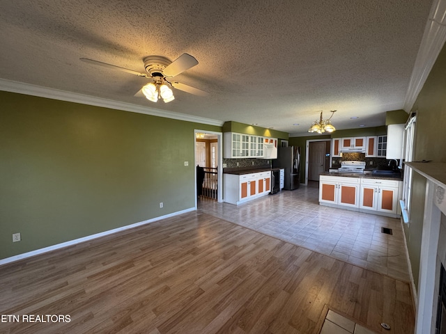 kitchen featuring decorative backsplash, freestanding refrigerator, dark countertops, and open floor plan