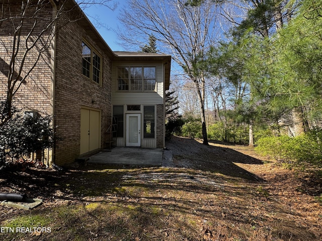 rear view of house with a patio and brick siding