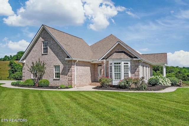 view of front facade with a front lawn, brick siding, and a shingled roof