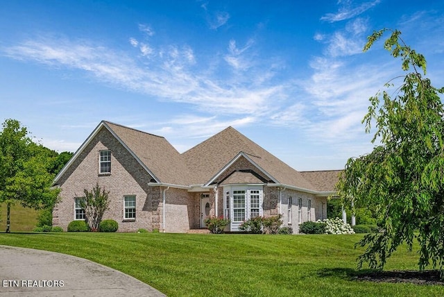 view of front of home featuring brick siding, a front yard, and a shingled roof