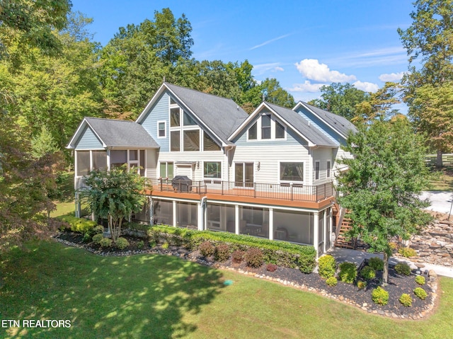 rear view of property featuring a wooden deck, a lawn, stairs, and a sunroom